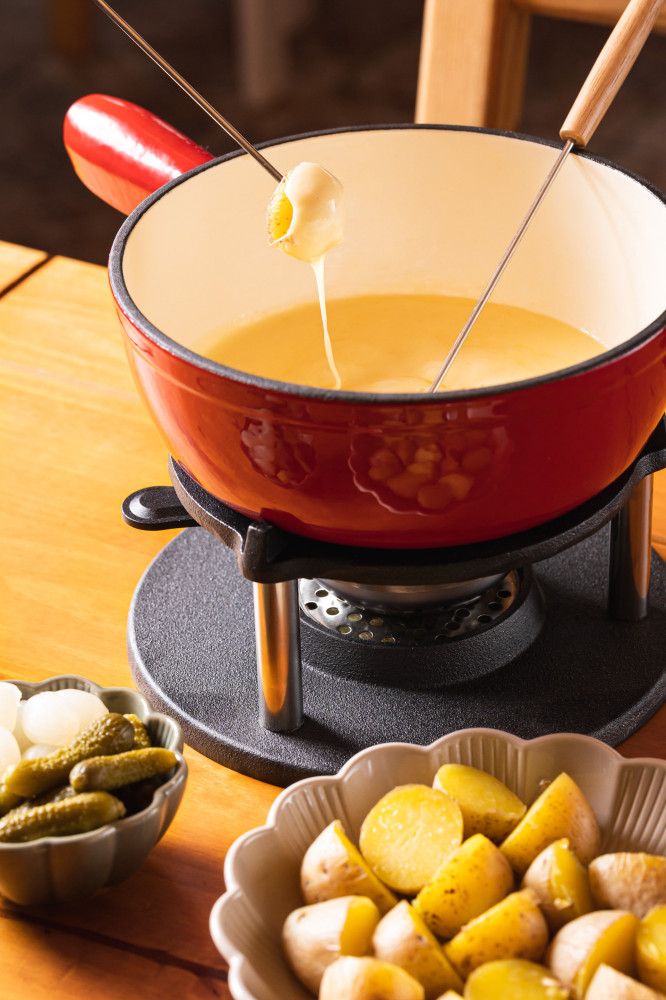 K raclette fondue jsou podávány brambory ve slupce, fokáča, okurky a cibulky.