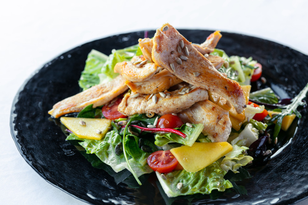 Mango salad with grilled chicken breast, tomatoes, cucumber, iceberg, letuchy and nuts